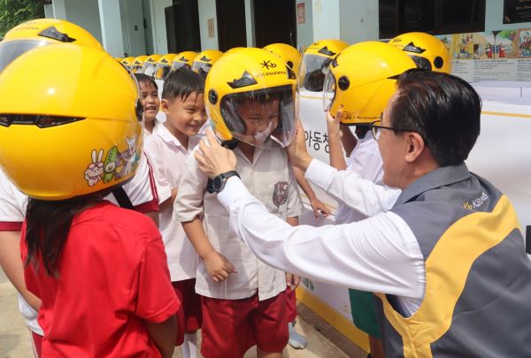 안전모 전달식에 참여한 조정래 KB손해보험 인니법인장이 Sinar Cahaya Kasih 학교 학생들에게 안전모를 씌워주고 있다. ⓒKB손해보험